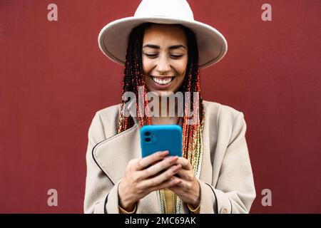 Bonne jeune fille africaine s'amusant à l'aide d'un smartphone mobile en extérieur Banque D'Images