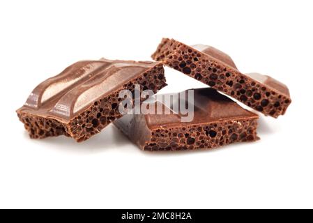 Morceaux de chocolat aéré cassé sur fond blanc gros plan. Chocolat Banque D'Images