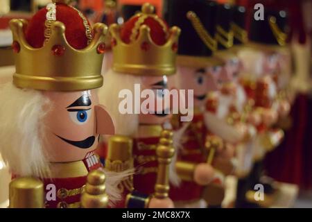 Une rangée de décorations de Noël traditionnelles en bois rouge et or portant une combinaison de couronnes et de chapeaux soldats. Banque D'Images