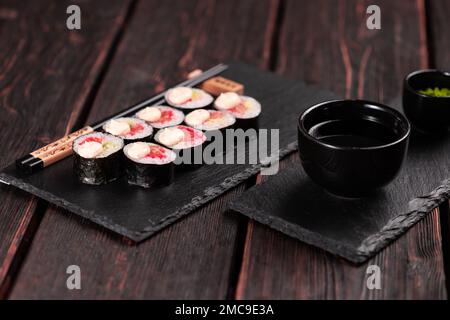 Petit sushi Maki avec avocat au saumon et caviar tobiko servi sur tableau noir - cuisine japonaise Banque D'Images