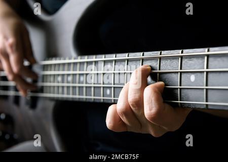 Guitare basse joueur main gros plan, leçon et thème de pratique. Jouer sur guitare électrique basse, musique live et concept de compétence. Vue rapprochée de l'ailette du guitariste Banque D'Images