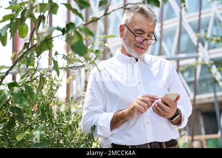 Un vieil homme d'affaires professionnel chevronné heureux utilisant un téléphone cellulaire utilisant un téléphone cellulaire en ville. Banque D'Images