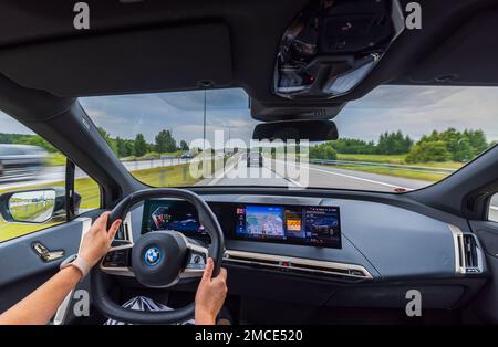 Vue des mains d'une femme conduisant une nouvelle BMW iX40 voiture électrique le long de l'autoroute. Suède. Banque D'Images