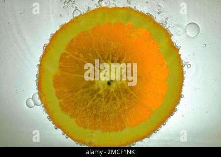 Gros plan d'une tranche d'orange juteuse sur fond blanc. Tranche d'orange dans de l'eau pétillante sur fond blanc, gros plan. Image macro horizontale Banque D'Images