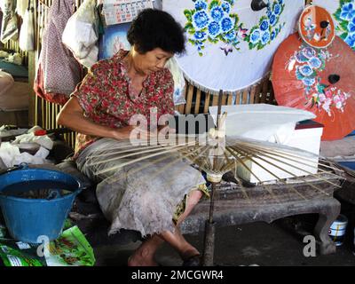 Un technicien de fabrication thaïlandais dessine la couleur de peinture sur un parapluie en papier fait à la main pour le spectacle et la vente dans un atelier de studio à Bo sang ou Borsang Umbrella vi Banque D'Images