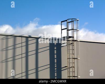 détail échelle d'accès au toit en aluminium avec cage de sécurité. boulonné sur un mur en béton blanc. longues ombres fortes dans un soleil lumineux de l'après-midi. construction de bâtiments Banque D'Images