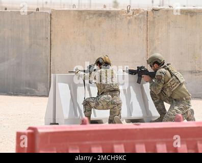 Deux défenseurs du 379e escadron des forces de sécurité expéditionnaires ont tiré derrière une barricade lors d'une manifestation de tir, de déplacement et de communication le 2 juillet 2022 à la base aérienne Al Udeid, Qatar. Les défenseurs ainsi que d'autres aviateurs du 379e EMSG ont montré comment avancer sur une cible tout en maintenant le feu et la communication. 379 AEW, 379th Air Expeditionary Wing, ACE, emploi de combat agile, Al Udeid, M-4 Carbine, MCA, aviateurs multi capables, Qatar, forces de sécurité, défenseurs, feu et mouvement, Banque D'Images