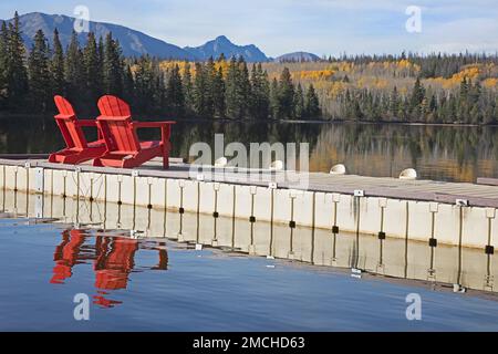 Chaises rouges sur un quai avec vue panoramique sur la nature surplombant le lac Pyramid, la forêt et les montagnes Rocheuses à l'automne, parc national Jasper, Alberta, Canada Banque D'Images