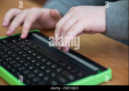 Un homme aveugle utilise un ordinateur doté d'un écran en braille et d'un clavier d'ordinateur. Périphérique inclus. Banque D'Images