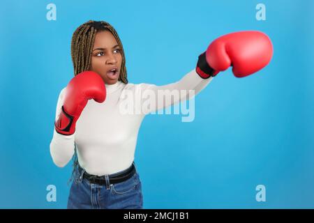 Une femme africaine agressive portant des gants de boxe frappe Banque D'Images