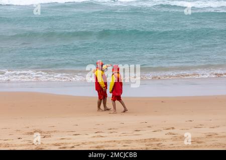 Manly Beach Sydney, deux sauveteurs volontaires de sauvetage de surf, homme et femme, s'est enveloppé contre les étés humides jour 2023, Sydney, Australie Banque D'Images