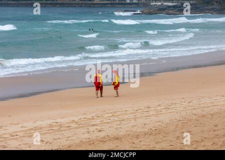 Manly Beach Sydney, deux sauveteurs volontaires de sauvetage de surf, homme et femme, s'est enveloppé contre les étés humides jour 2023, Sydney, Australie Banque D'Images