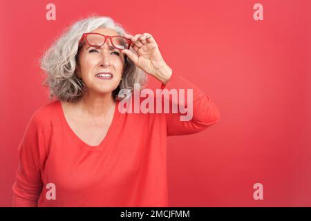 Femme levant ses lunettes pour voir de loin Banque D'Images