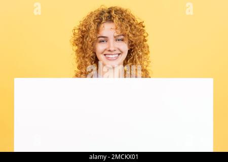 Femme souriante avec cheveux bouclés tenant un panneau vierge Banque D'Images