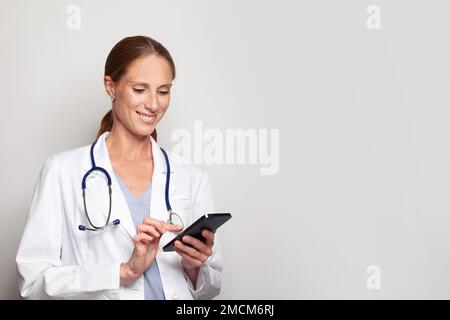 Gai confiant heureux mature adulte moyen médecin travailleur médical tenant smartphone dans sa main, portrait de femme Banque D'Images