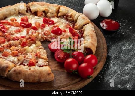 Pizza cuite avec ingrédients à côté de faire sauce tomate, mozzarella, tomates, huile d'olive, fromage, épices, servies sur une table rustique en bois. Forme plate Banque D'Images