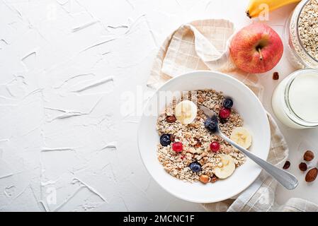 Un bol de granola et de muesli secs servi avec des fruits frais et des noix. Plaque à flocons d'avoine. Alimentation saine, alimentation. Vue de dessus. Banque D'Images