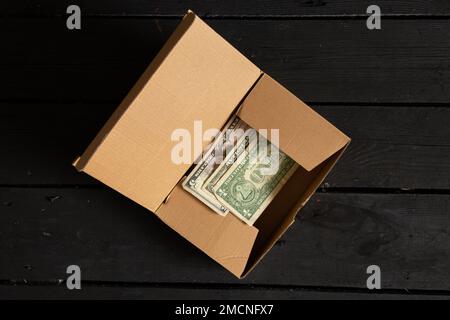 les dollars américains se trouvent dans une boîte corton marron sur une table en bois noir, l'argent dans une boîte sur la table Banque D'Images