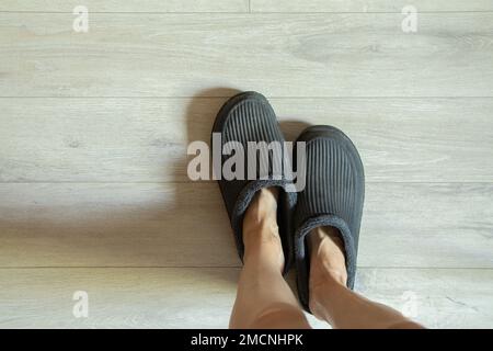 pieds féminins sur le sol en pantoufles, pieds en pantoufles sur le sol à la maison Banque D'Images