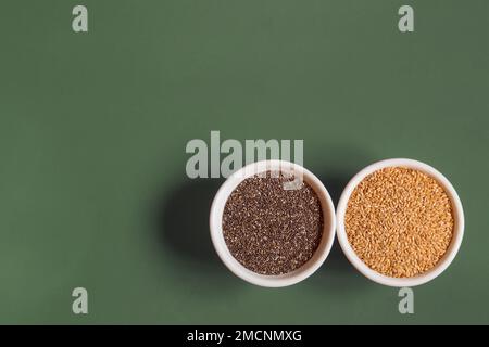 Vue de dessus du chia entier et des graines de lin dans de petits bols ronds en céramique blanche, côte à côte, sur un arrière-plan de studio avec espace de copie. Des graines saines à manger. Banque D'Images