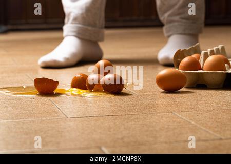 Casse accidentelle d'oeufs sur le sol de la cuisine Banque D'Images