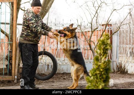 Un homme formant son chien de berger allemand à l'extérieur Banque D'Images