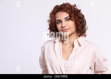 Portrait d'une fille qui sourit doucement. Cheveux bouclés courts. Banque D'Images