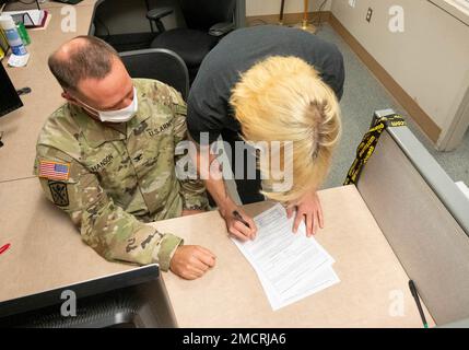 Le colonel Ryan Hanson, commandant de la garnison de fort Jackson, à gauche, et son fils Pvt. Bradshaw Hanson, à droite, signent son serment d'enrôlement après la cérémonie d'assermentation de 8 juillet 2022, à la station de traitement de l'entrée militaire de fort Jackson. Le colonel Hanson a été invité à livrer l'serment d'enrôlement à son fils et à d'autres qui ont récemment contracté pour devenir des soldats. Banque D'Images