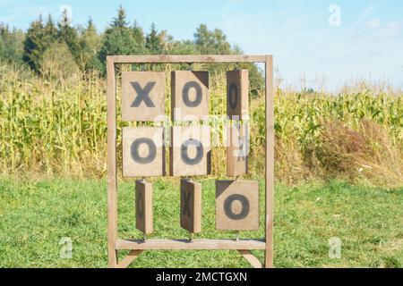 Immense stand vertical de bois TIC-tac-TOE et crosses de jeu installé près des champs de maïs en plein air dans le parc de champ en été ensoleillé jour. Jeux de société, Banque D'Images