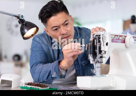 Mechanic repairing senior industrial sewing machine Banque D'Images