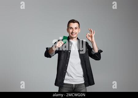jeune homme tenant une carte de crédit et faisant un geste correct Banque D'Images