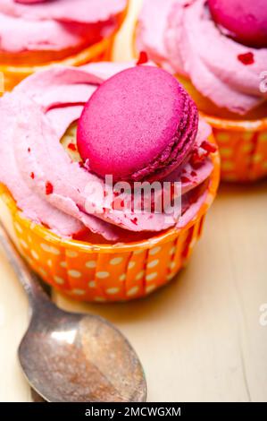 Gâteau aux fruits frais et à la crème de baies roses avec macaron sur une table en bois rustique Banque D'Images