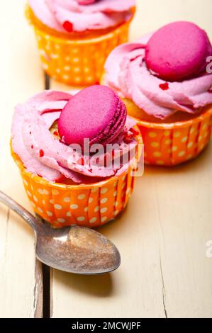 Gâteau aux fruits frais et à la crème de baies roses avec macaron sur une table en bois rustique Banque D'Images