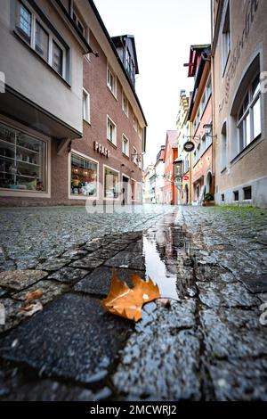 Rue pavée avec flaques et feuilles dans l'eau par temps pluvieux, île de Lindau, lac de Constance, Allemagne Banque D'Images