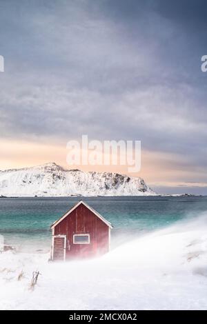Cabane de pêche Red Rorbuer sur la plage dans la neige, Ramberg, Flakstadoya, Lofoten, Norvège Banque D'Images