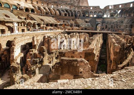 Les touristes explorent l'intérieur du Colisée de Rome, en Italie, avec ses structures souterraines exposées. Banque D'Images