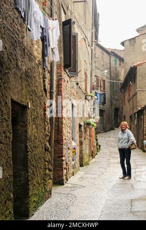 Scène de rue médiévale avec lavage suspendu aux fenêtres dans un passage, un piéton, Roccatederighi Mountain village, Toscane, Italie, Banque D'Images