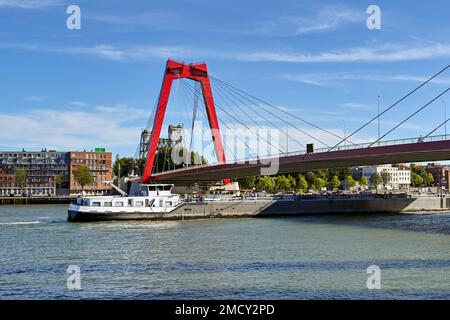 Rotterdam, Nertherlands - août 2022 : navire de cargaison transportant des conteneurs d'expédition sur la rivière Nieuwe Maas passant par le pont suspendu de Willemsbrug Banque D'Images