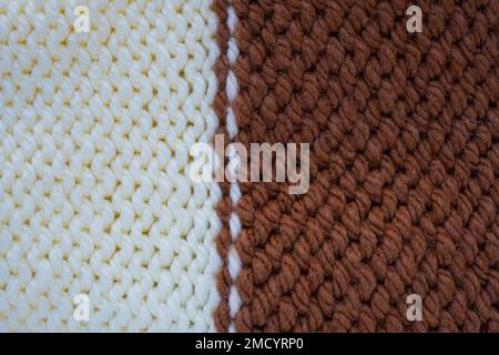 Motif en laine. Tissu tricoté fait main, texture de fond en laine blanche et brune. Surface texturée, verso ou mauvais côté. Accessoires chauds, Banque D'Images