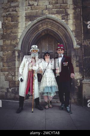 Un groupe de steampunks très habilement habillés debout devant une vieille porte voûtée. Banque D'Images