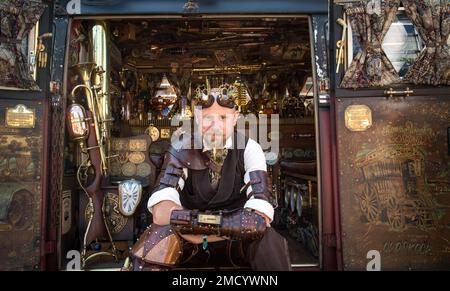 Un steampunk se trouve sur le côté de sa fourgonnette VW Camper montrant son intérieur magnifique. Science fiction, aventurier, temps voyageur concept. Banque D'Images