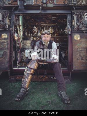 Un steampunk se trouve sur le côté de sa fourgonnette VW Camper montrant son intérieur magnifique. Science fiction, aventurier, temps voyageur concept. Banque D'Images