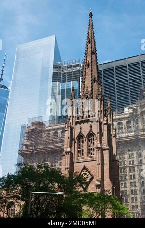 L'église emblématique de trinity contre un paysage urbain moderne de bâtiments dans la ville de New York par une journée ensoleillée. Banque D'Images