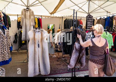 Femme naviguant dans un gilet en fourrure et des vêtements sur l'exposition au marché local, hebdomadaire, d'été, traditionnel dans le village de San Pantaleo, Sardaigne, Italie Banque D'Images