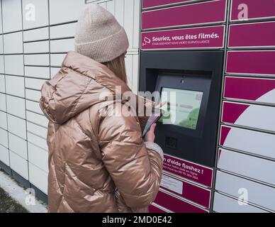 Loriol sur Drome, France - 14 janvier 2023: Enlèvement d'une parcelle d'un mondial "Relais casier par une jeune femme. Relais mondial de casiers. Caisse de pick-up. Banque D'Images