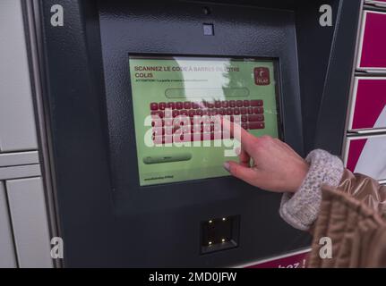 Loriol sur Drome, France - 14 janvier 2023: Enlèvement d'une parcelle d'un mondial "Relais casier par une jeune femme. Relais mondial de casiers. Caisse de pick-up. Banque D'Images