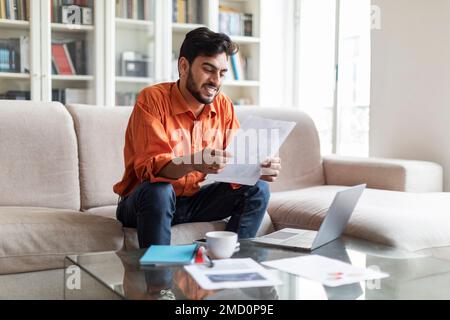Bon garçon arabe travaillant à domicile, vérifiant les papiers Banque D'Images