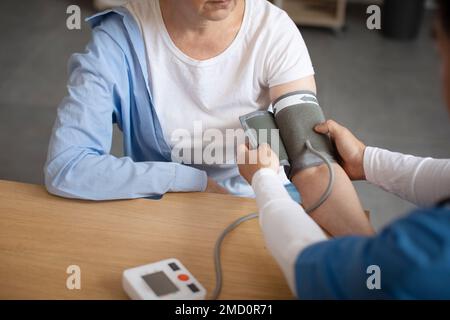 Le médecin mesure la pression artérielle avec le tonomètre de la patiente européenne senior à l'intérieur du bureau de la clinique Banque D'Images