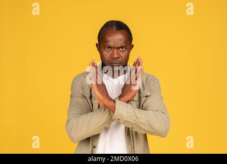 Un homme afro-américain en colère, confiant et triste, d’âge moyen, aux armes croisées, signe d’arrêt Banque D'Images