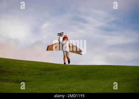 Un petit garçon est en train de jouer et de rêver de voler au-dessus des nuages. Pilote aviateur enfant avec un avion jouet joue sur la nature d'été. Enfant jouant avec Banque D'Images